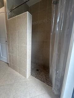 full bathroom with a tile shower and tile patterned flooring