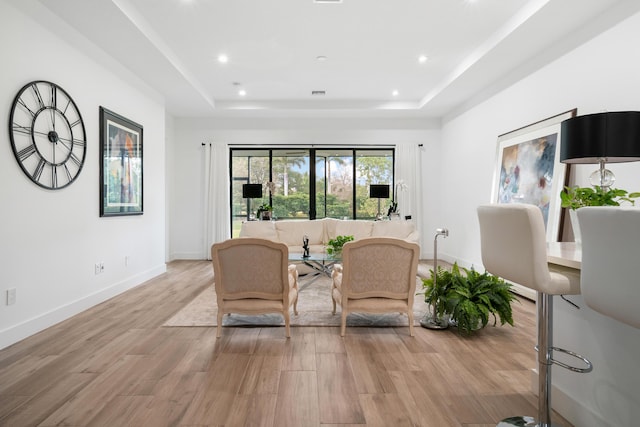 living area with a tray ceiling, recessed lighting, baseboards, and light wood-type flooring