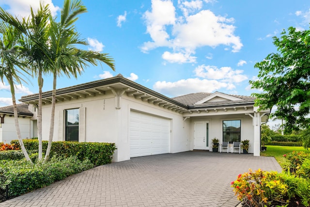 view of front of home featuring stucco siding, an attached garage, and decorative driveway