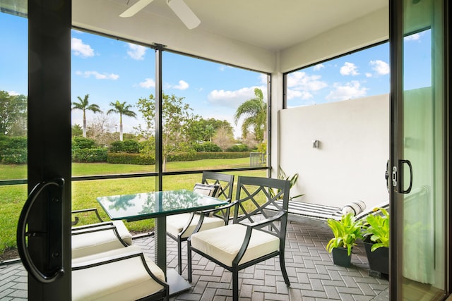 sunroom / solarium with outdoor dining space and ceiling fan