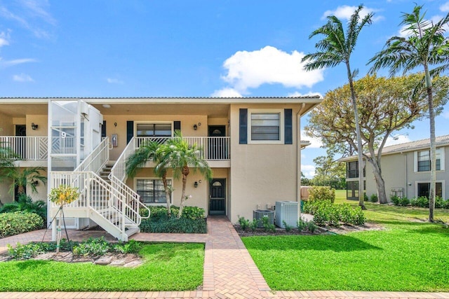 9 Stratford Dr Unit D, Boynton Beach, FL 33436 - view of front of home with stairway, stucco siding, central AC, and a front yard