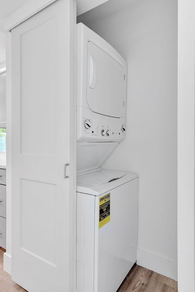 12938 Ellison Wilson Rd, North Palm Beach, FL 33408 - washroom with stacked washing machine and dryer and wood finished floors