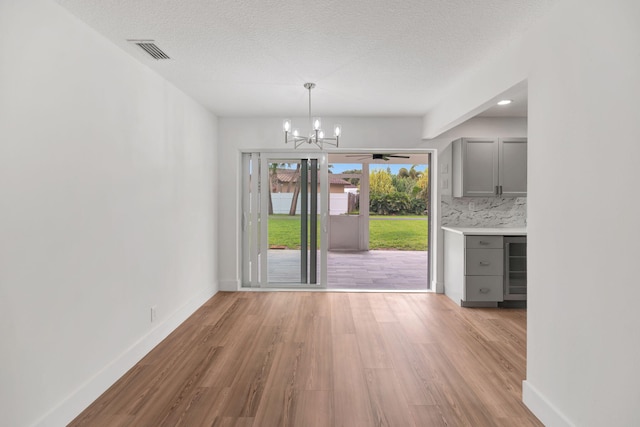 12938 Ellison Wilson Rd, North Palm Beach, FL 33408 - unfurnished dining area with light wood-style floors, a chandelier, baseboards, and a textured ceiling