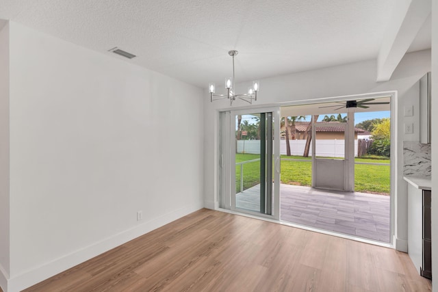 12938 Ellison Wilson Rd, North Palm Beach, FL 33408 - unfurnished dining area with light wood-style flooring, a chandelier, baseboards, and a textured ceiling