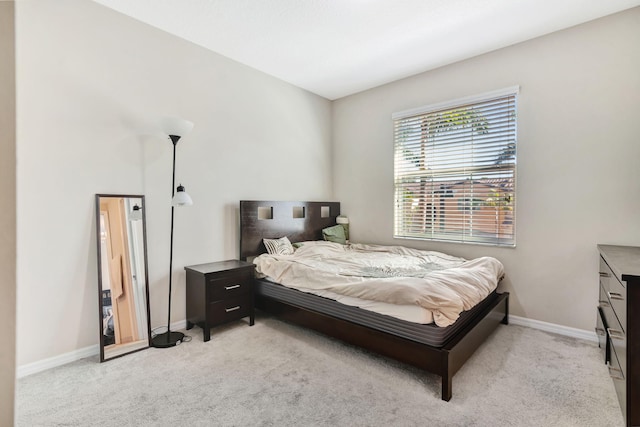 bedroom with light colored carpet and baseboards