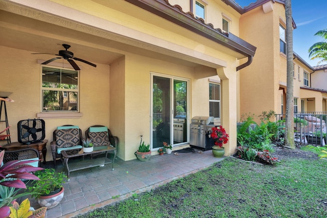 view of exterior entry featuring a patio area, stucco siding, a ceiling fan, and fence