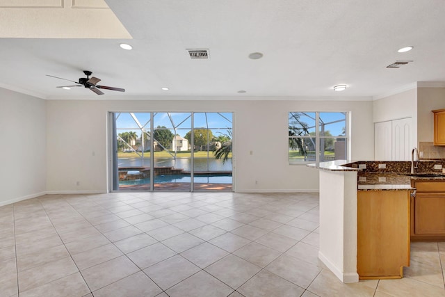 kitchen with open floor plan, baseboards, and crown molding