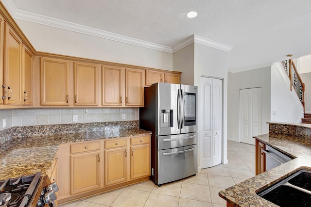 kitchen with light tile patterned floors, ornamental molding, dark stone countertops, appliances with stainless steel finishes, and decorative backsplash