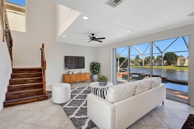 living area with light tile patterned flooring, ceiling fan, ornamental molding, and visible vents