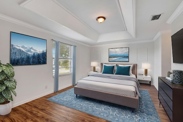 bedroom with crown molding, visible vents, a raised ceiling, and wood finished floors