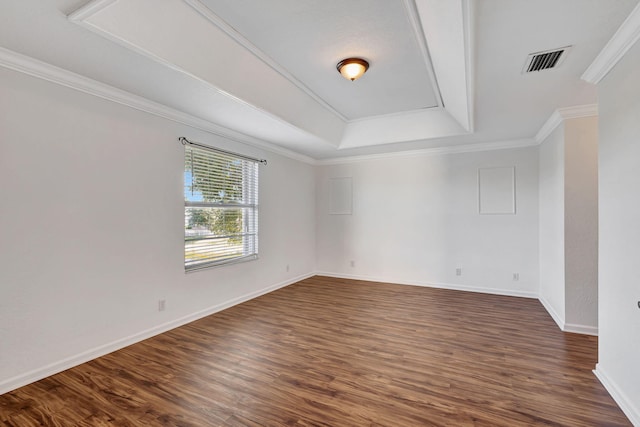 empty room featuring visible vents, a tray ceiling, crown molding, and dark wood finished floors