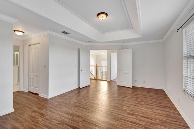 empty room with a tray ceiling, dark wood-style flooring, baseboards, and visible vents