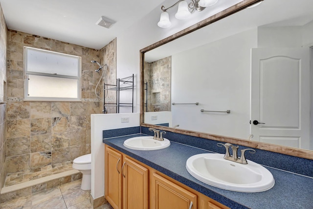 bathroom with a sink, visible vents, toilet, and tiled shower
