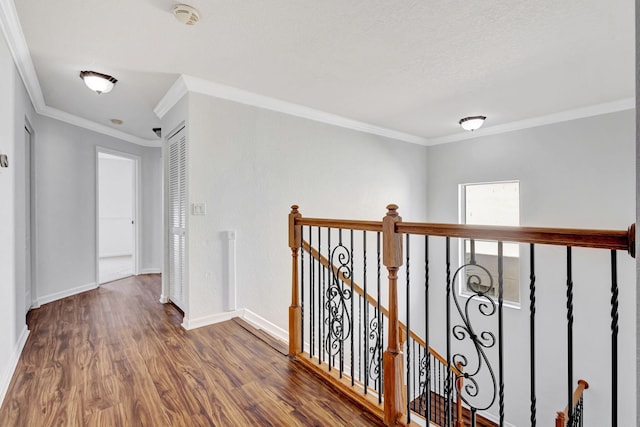 corridor featuring an upstairs landing, baseboards, crown molding, and wood finished floors