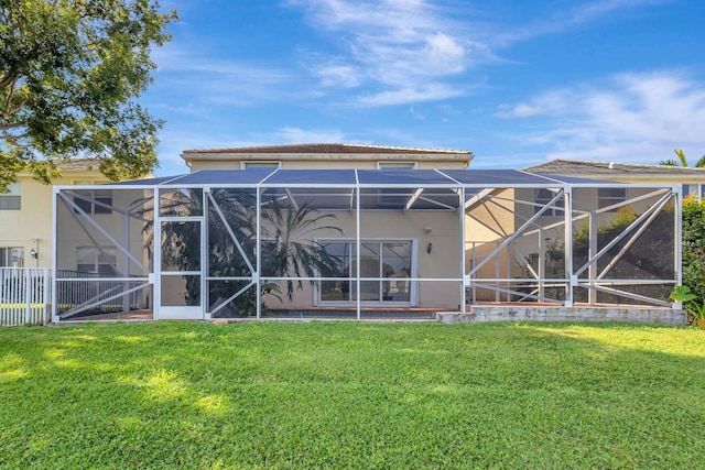 back of house featuring a tile roof, stucco siding, a lawn, and a lanai