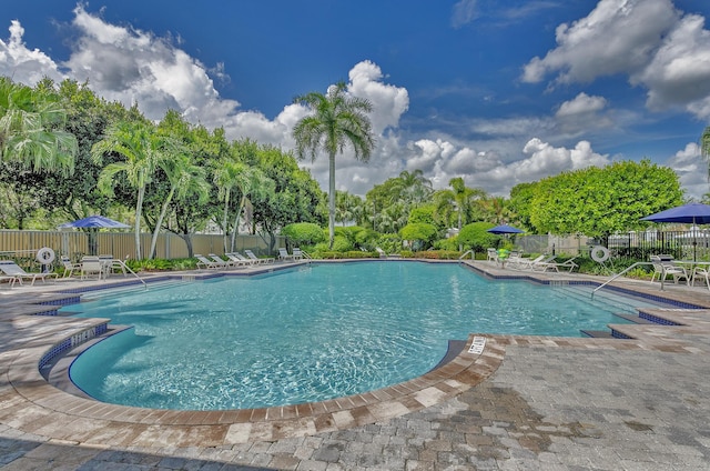 community pool with a patio and fence
