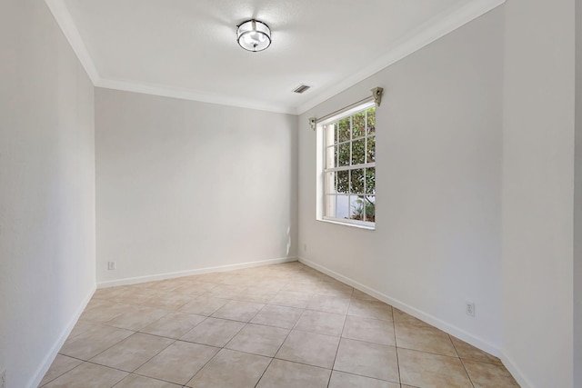 empty room with light tile patterned flooring, baseboards, ornamental molding, and visible vents