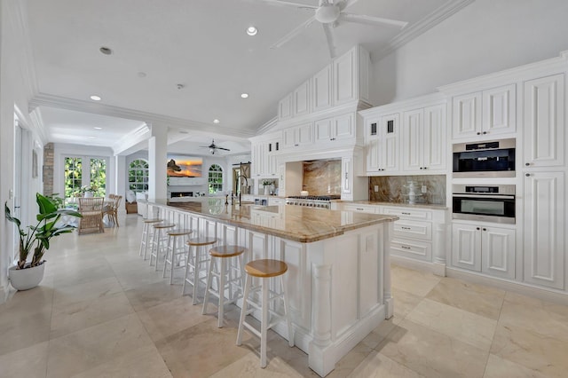15082 Tall Oak Ave, Delray Beach, FL 33446 - kitchen featuring crown molding, light stone counters, a sink, a ceiling fan, and tasteful backsplash
