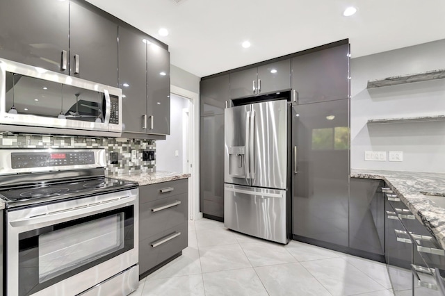 kitchen featuring light stone counters, stainless steel appliances, gray cabinetry, and decorative backsplash