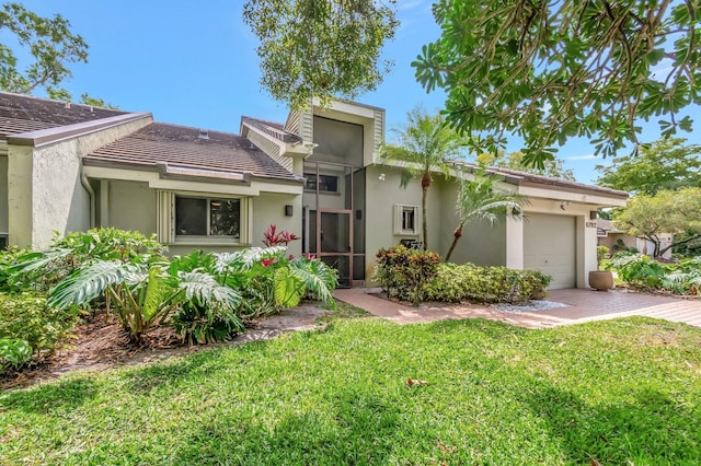 view of front of house featuring a front yard, stucco siding, an attached garage, and a tiled roof