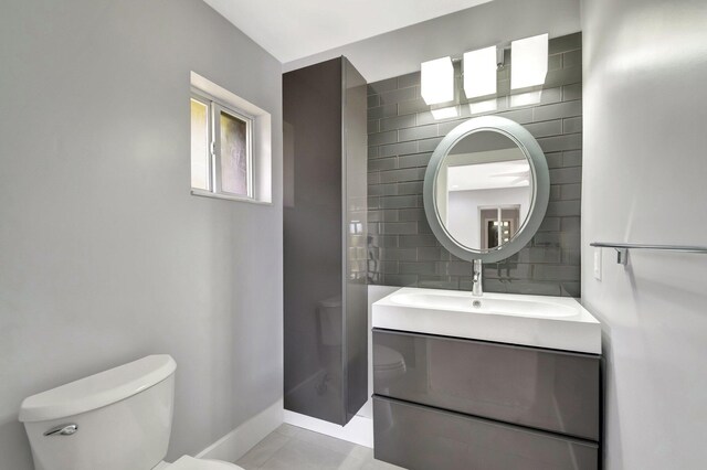 bathroom with vanity, tile walls, toilet, baseboards, and backsplash