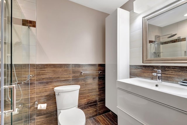 bathroom with a shower stall, toilet, vanity, and tile walls