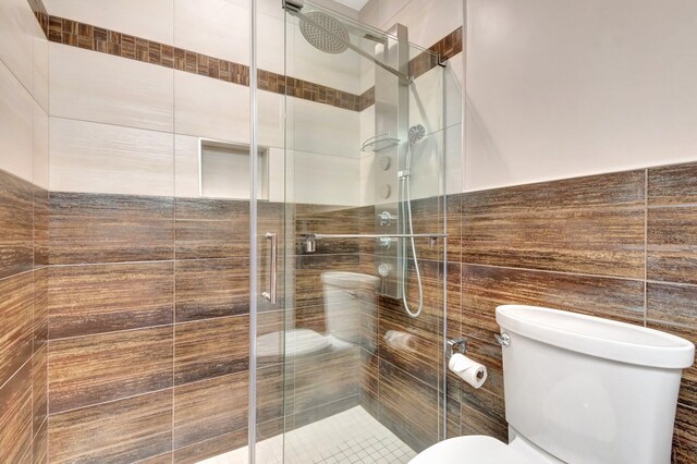 full bath featuring a stall shower, toilet, and tile walls