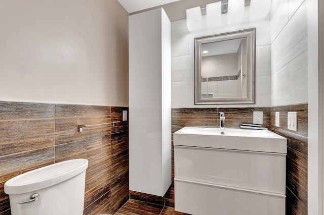 bathroom featuring tile walls, a wainscoted wall, toilet, and vanity