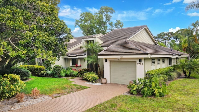 view of front of home with a tiled roof, stucco siding, decorative driveway, and a garage