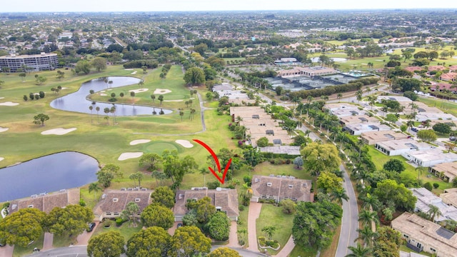 drone / aerial view featuring golf course view, a water view, and a residential view