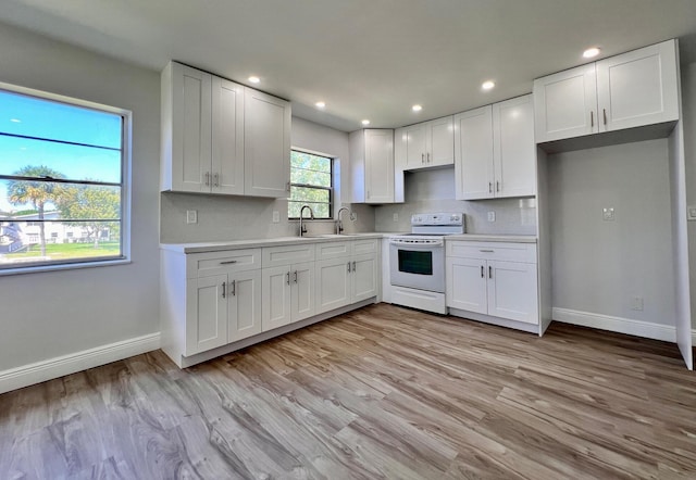 kitchen with light countertops, white cabinets, backsplash, and white range with electric cooktop