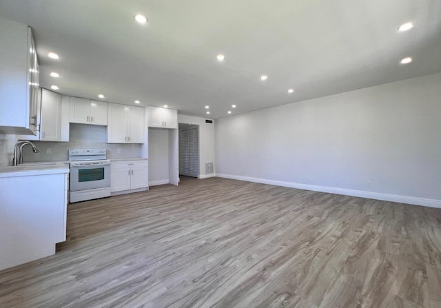 kitchen with recessed lighting, a sink, light countertops, white cabinets, and white range with electric stovetop