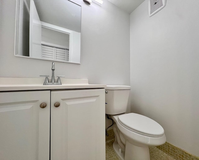 half bath featuring visible vents, toilet, and vanity