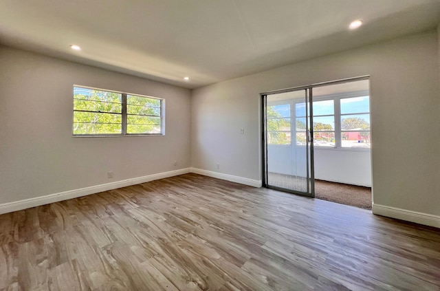 spare room with recessed lighting, baseboards, and wood finished floors