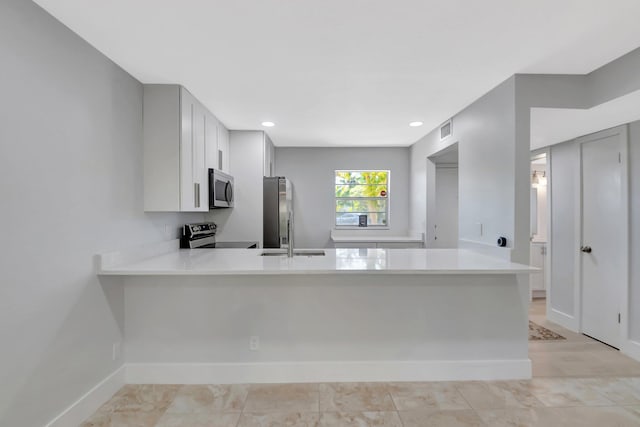 2601 NE 3rd Ct Unit 105, Boynton Beach, FL 33435 - kitchen with stainless steel appliances, a peninsula, light countertops, baseboards, and a sink