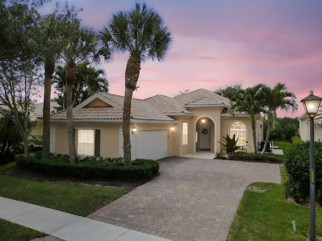 8378 Xanthus Ln, Wellington, FL 33414 - mediterranean / spanish-style house with stucco siding, a garage, driveway, a tile roof, and a lawn
