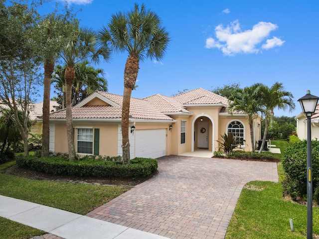 8378 Xanthus Ln, Wellington, FL 33414 - mediterranean / spanish home featuring stucco siding, an attached garage, decorative driveway, a tiled roof, and a front lawn