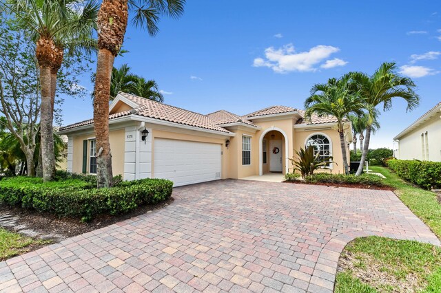 8378 Xanthus Ln, Wellington, FL 33414 - mediterranean / spanish-style home with an attached garage, stucco siding, a tiled roof, and decorative driveway