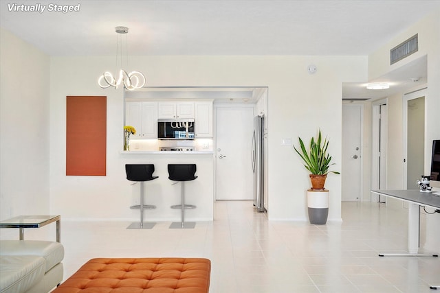 kitchen featuring light countertops, pendant lighting, stainless steel appliances, visible vents, and white cabinets