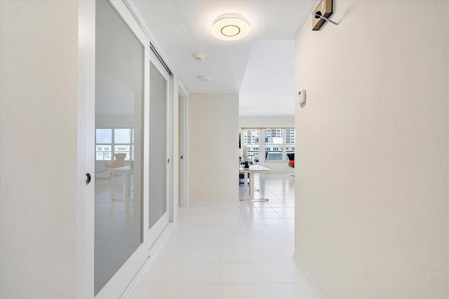corridor featuring light tile patterned flooring, a wealth of natural light, and baseboards