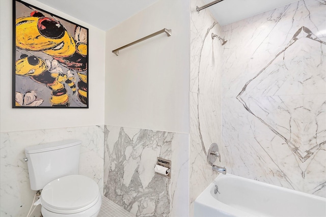 bathroom with toilet, a wainscoted wall, tile walls, and shower / washtub combination