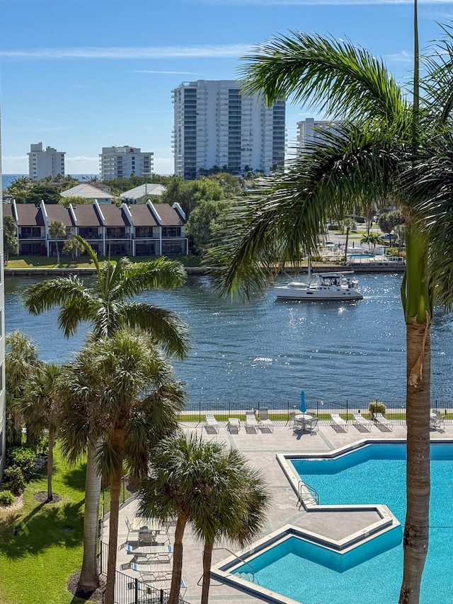 community pool featuring a patio area, fence, and a water view