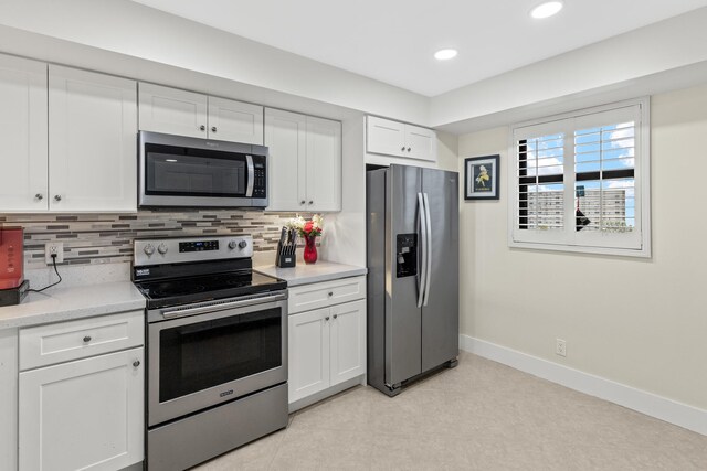 kitchen with decorative backsplash, baseboards, white cabinetry, and stainless steel appliances