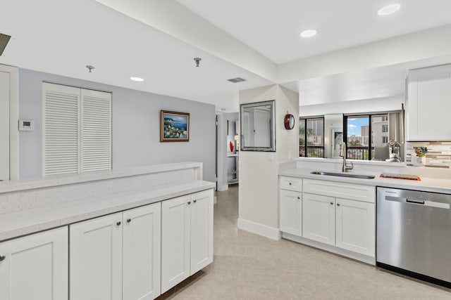 kitchen featuring stainless steel dishwasher, a sink, white cabinetry, and recessed lighting