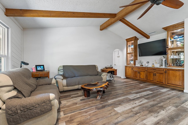 living room featuring dark wood finished floors, visible vents, a ceiling fan, lofted ceiling with beams, and a textured ceiling