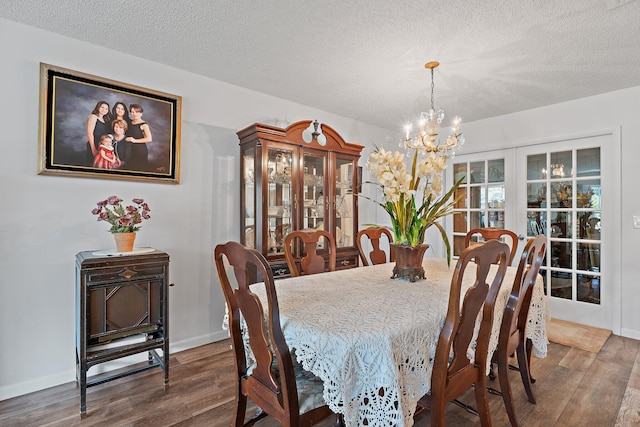 dining space featuring an inviting chandelier, a textured ceiling, wood finished floors, and french doors