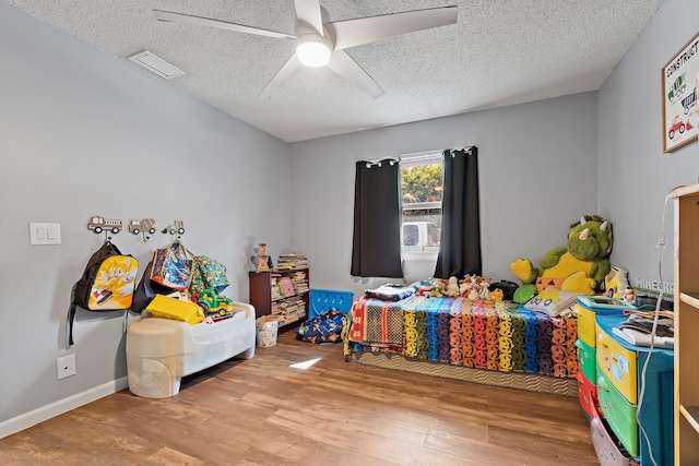 bedroom featuring a ceiling fan, wood finished floors, a textured ceiling, and visible vents