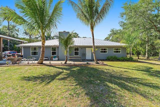 single story home with metal roof, a patio, a front yard, stucco siding, and a standing seam roof