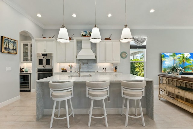 9129 SW Pepoli Way, Port Saint Lucie, FL 34987 - kitchen featuring custom exhaust hood, double oven, wine cooler, ornamental molding, and recessed lighting