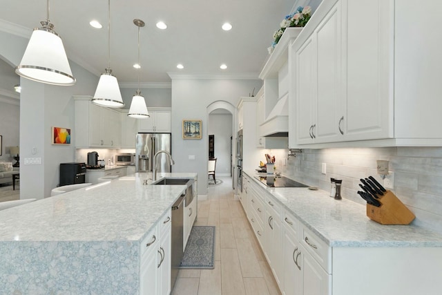 9129 SW Pepoli Way, Port Saint Lucie, FL 34987 - kitchen with premium range hood, appliances with stainless steel finishes, arched walkways, ornamental molding, and a spacious island